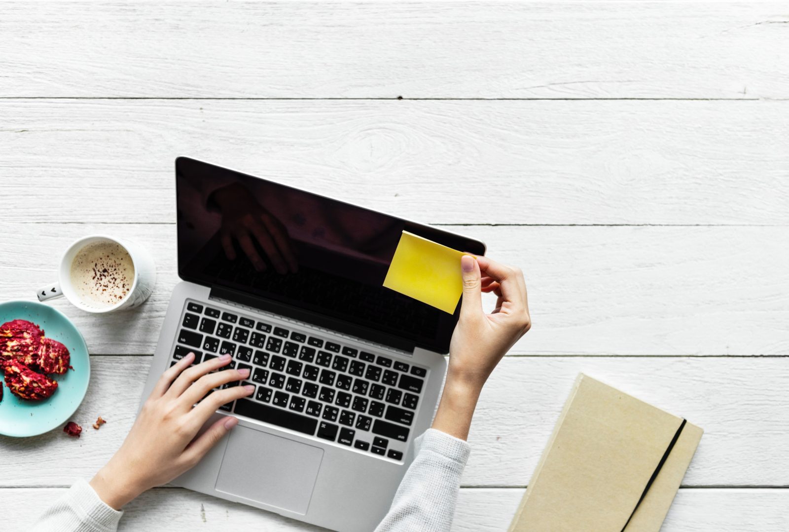 person putting sticky notes on MacBook