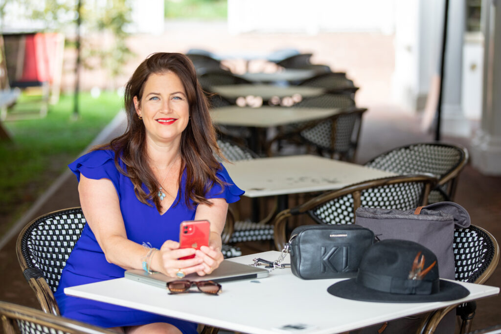 Claire Winter at table with phone smiling