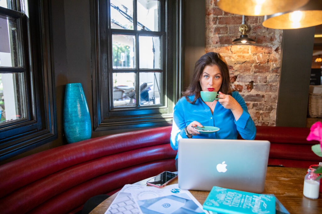 Claire drinking coffee in front of laptop