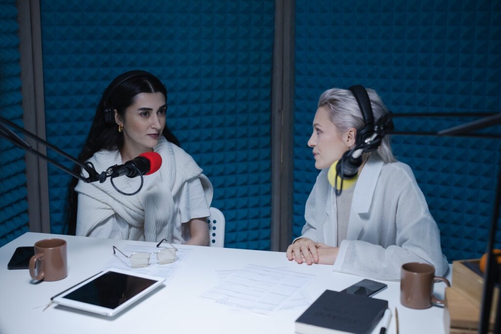 Two women face to face with microphones talking