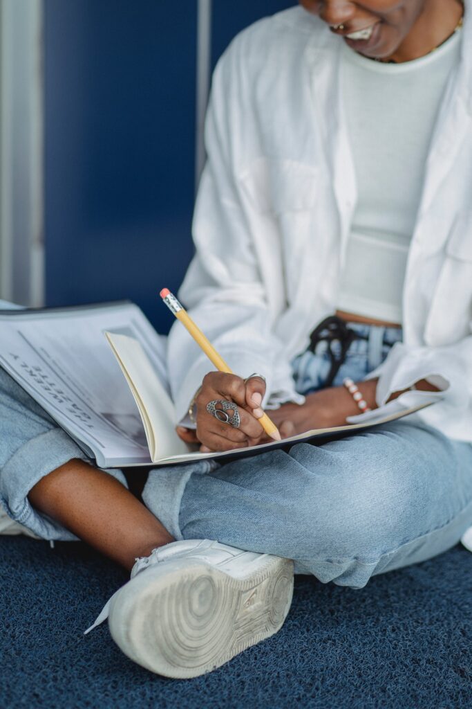 Woman sitting crosslegged writing into notebook