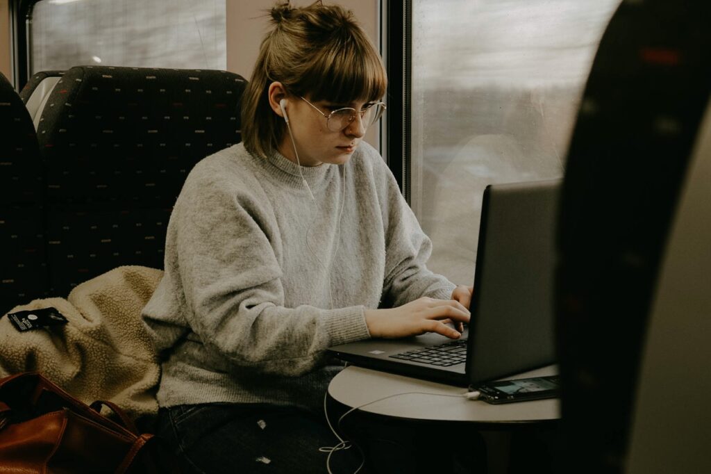 Woman typing on laptop with headphone on