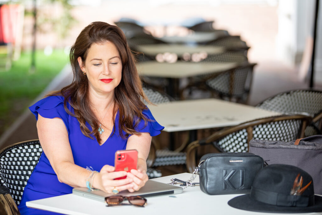 Claire Winter sitting at table looking at phone smiling