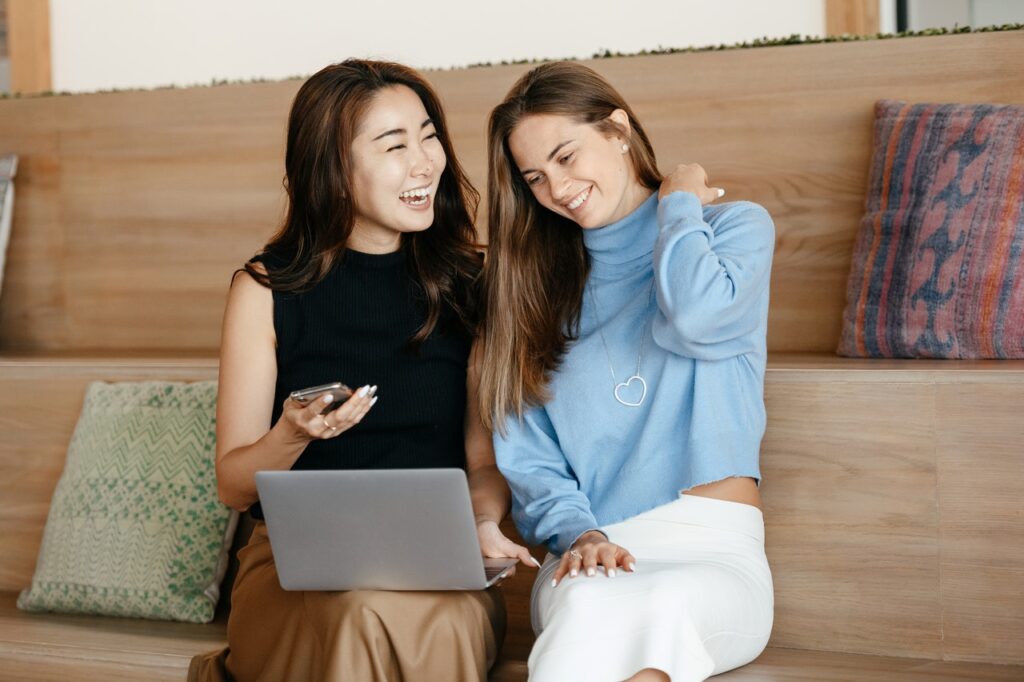 Two young happy women looking at their phones