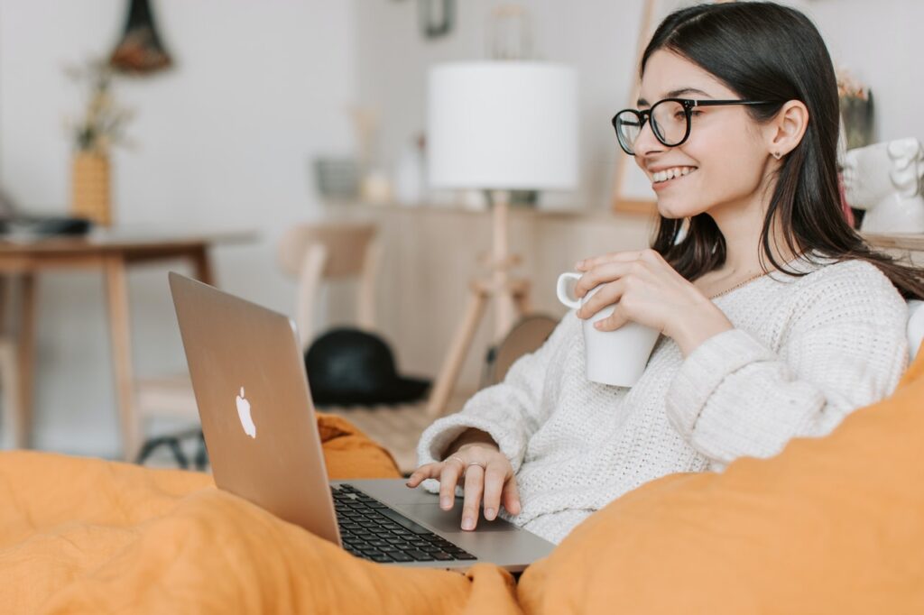 Happy woman drinking coffee in front of laptop