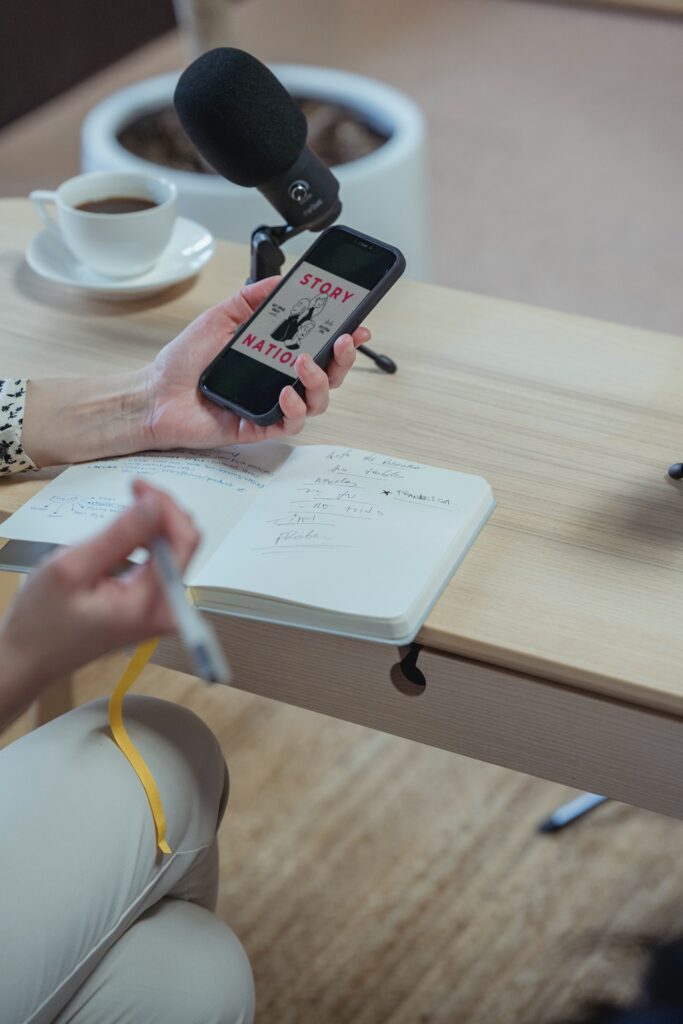 Woman looking at phone and writing in notepad