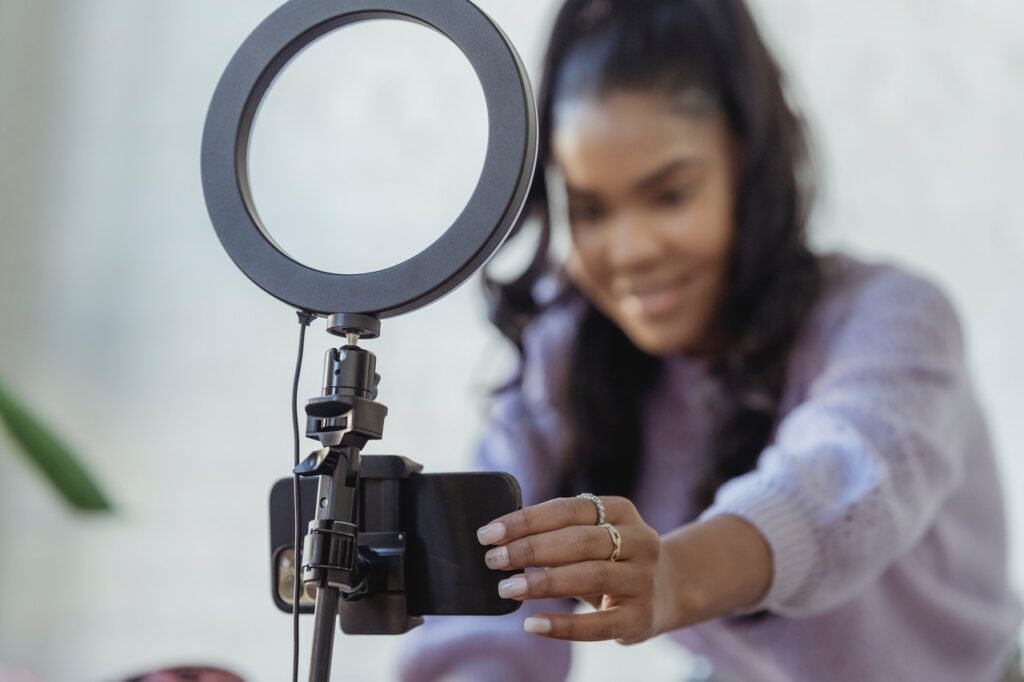 Woman setting up a camera phone on a stand with ring light above it